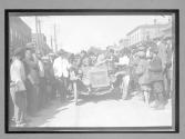 [auto racers surrounded by spectators in town "#63"]