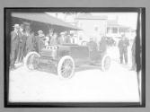 [auto racer in auto surrounded by spectators]