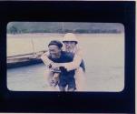 [Chapin, holding camera, being carried across river]