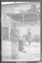 [Man sitting on dock pilings, buildings beyond]