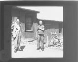 [Civilian standing next to young prisoner of war showing number tattooed on arm, Buchenwald Concentration Camp]