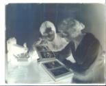 Two women looking at photo album next to an Kodak Autographic camera