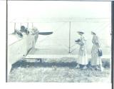 Women photographing men in biplane