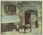 [Street scene with two women and a donkey]