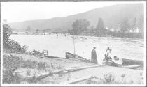Men in river with logs, people in boats foreground, Grand Cascapedia Trip