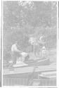 George Eastman and Watson Newhall watching construction of platform for motion picture camera on canoes, Grand Cascapedia Trip
