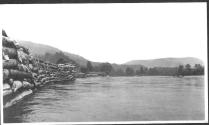 Logs stacked along river, Grand Cascapedia Trip