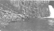 Companions fishing near waterfall, Wyoming Trip