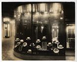 [Illuminated window display of men's hats]
