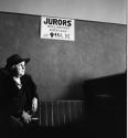 [Woman standing below sign for jurors]