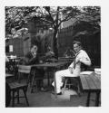 [Two men seated at an outdoor table]