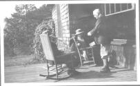George Eastman talking to seated guests on porch, Oak Lodge Trip