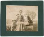 [Woman seated outdoors with two dogs]