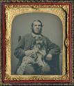[Seated man with small dog on his lap]