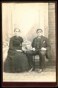[Man and woman seated in studio with blackbird in cage]
