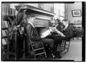 [Three men reading by fireplace]