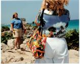 [Woman photographing another woman, standing on the beach]