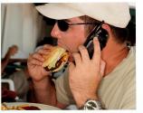 [Man on cell phone eating a hamburger]