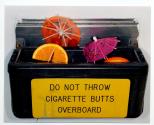 [Recepticle for discarding cigarette butts containing cocktail fruit and small paper umbrellas]