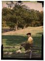 [Boy with rifle sitting on fence]