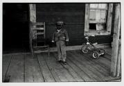Young boy with tricycle on porch