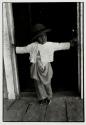 Young sharecropper child wearing a hat, in a doorway