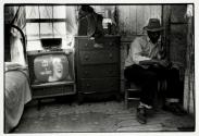 [Man sitting in room, television set on]