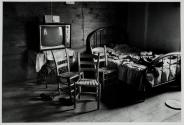 [Interior with bed, three chairs, television]