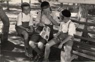 [Three Hasidic Jewish boys seated on a bench]