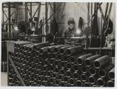 [Woman making ammunition cylinders in factory]