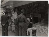 [Spain, two soldiers, an old man and a young woman at newstand]