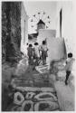 [Greece, Island of Mykonas, children walking up rocky road towards windmill]