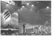 [Speaker at a podium at large political rally, in France]