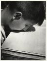 At a home for war-wounded children in Rome, a blind boy whose arms had to be amputated reads Braille with his lips.