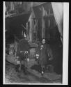 [Street scene, man and woman passing each other]