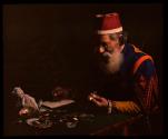 [Costumed man examining jewelry (pawnbroker?)]