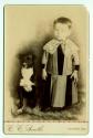 [Child with lace collar, posed with dog]