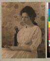 [Woman, possibly Elinor Castle, seated in front of flower wallpaper]