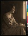 [Woman in dress seated in profile]