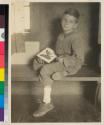 [Boy holding framed butterfly]