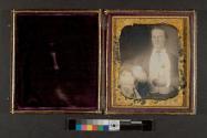 [Young man in suit with arm resting on pedestal]