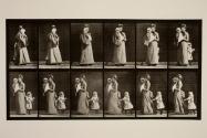 Walking, carrying child, turning around; another child (70) holding on to dress of 93