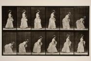 Stooping and lifting hand'chief; parasol in l. hand