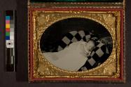 [Child sleeping (?) on checked blanket. Identified as Mamie D. Lee]