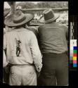[Men from behind, viewing event in a corral]