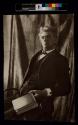 [Man sitting on chair holding a book]