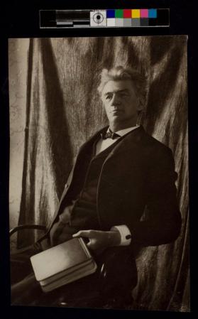 [Man sitting on chair holding a book]