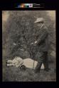 [Woman laying on ground and man standing with cane]