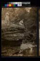 [Two women with older man looking over the side of a small cliff]