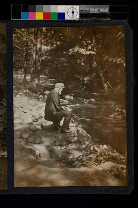 [Elderly man fishing at edge of lake]